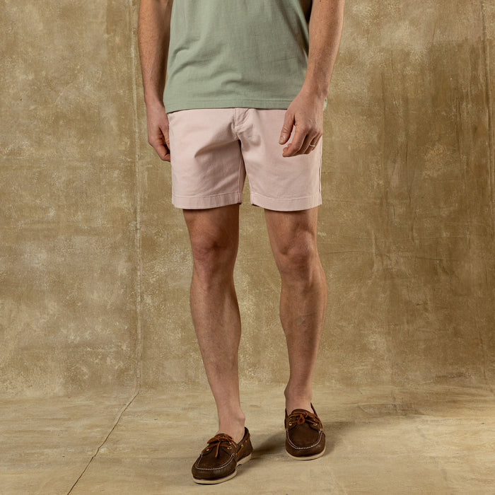 Light pink chino shorts worn with green t-shirt and brown boat shoes, studio shot