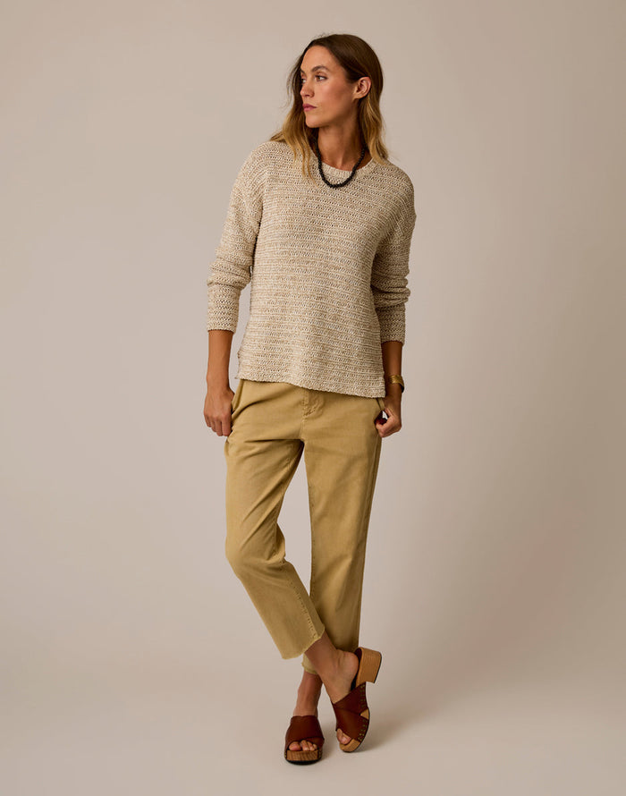 Woman wearing light beige marled knit sweater with long sleeves and relaxed fit