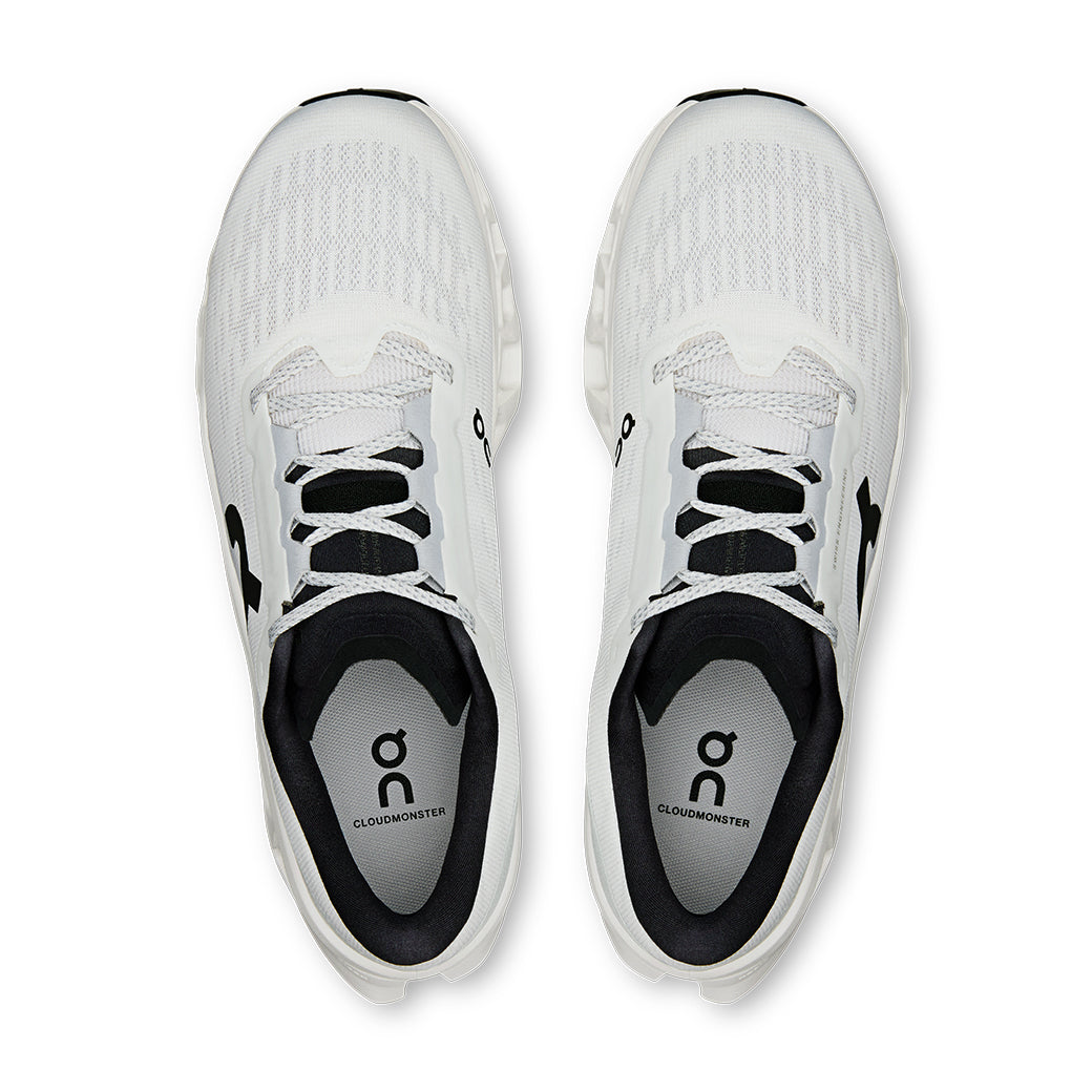 Light colored athletic running shoes with mesh upper and black laces, top-down view