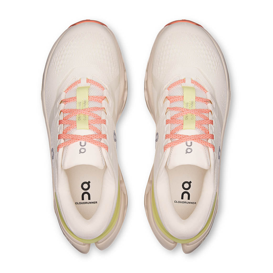 Light colored running shoes with orange laces and green accents, top-down view showing both shoes