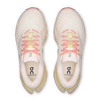 Light colored running shoes with orange laces and green accents, top-down view showing both shoes