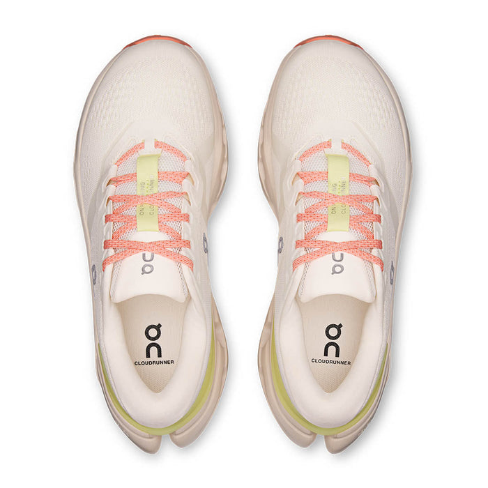 Light colored running shoes with orange laces and green accents, top-down view showing both shoes