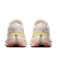 Light colored running shoes shown from rear view with textured outsole and yellow accent details
