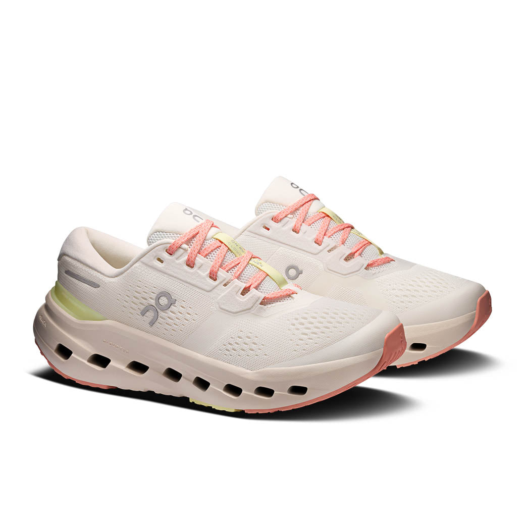 Light colored running shoes with coral laces and distinctive chunky foam sole with air holes