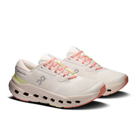 Light colored running shoes with coral laces and distinctive chunky foam sole with air holes