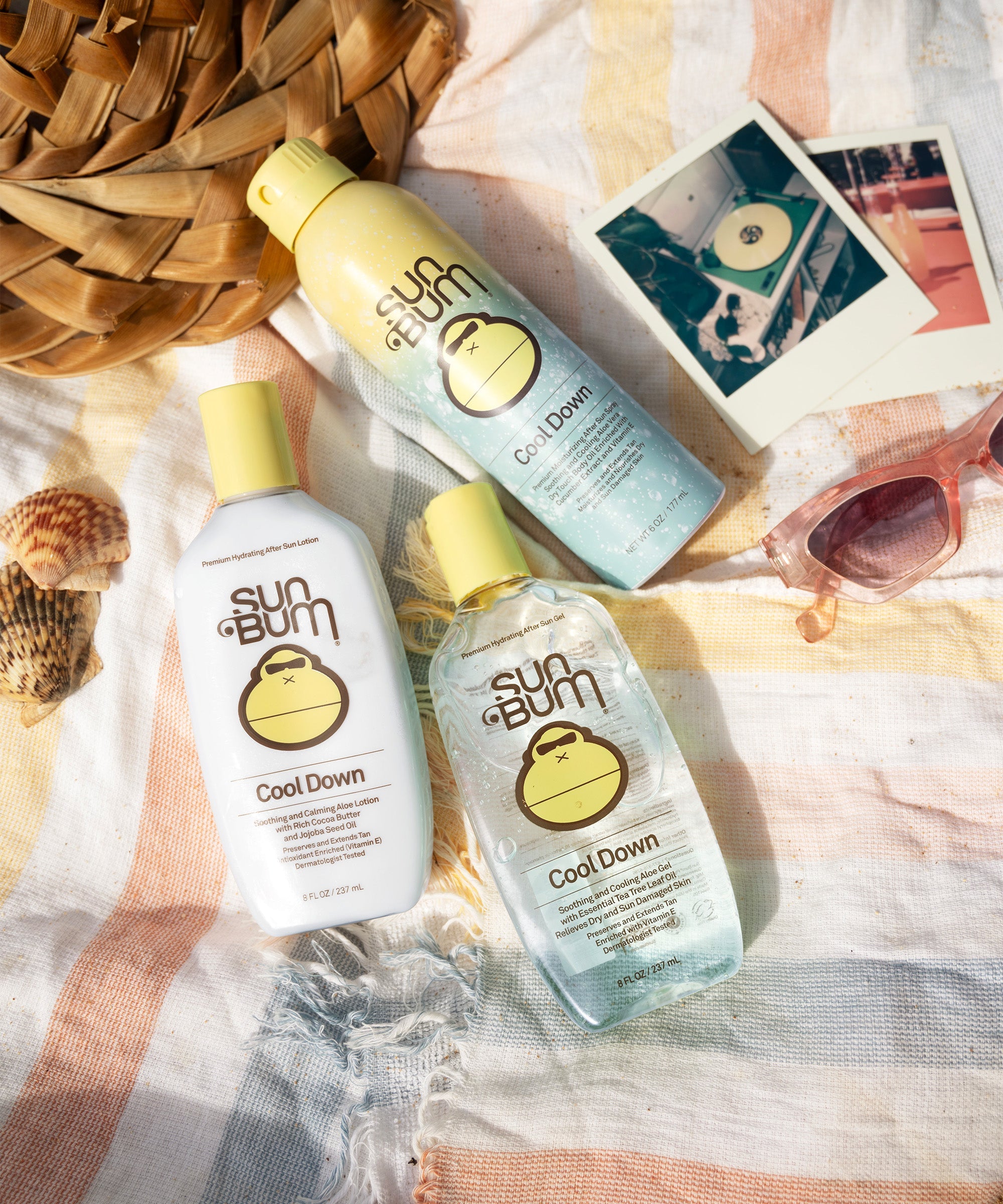 Three after-sun cooling gel bottles in yellow and teal packaging on beach towel with sunglasses