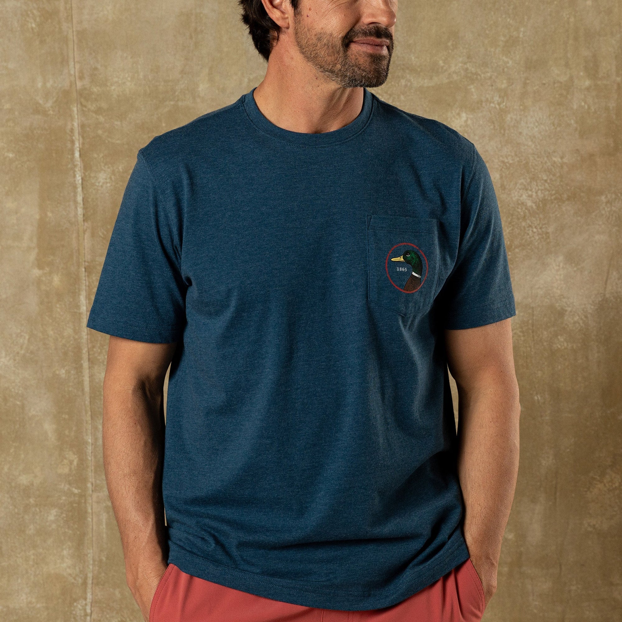 Heathered blue short sleeve t-shirt with chest pocket and small circular logo patch