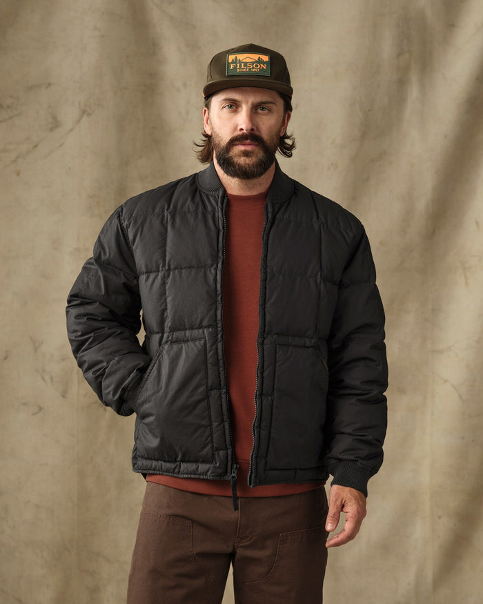 Men's black quilted puffer bomber jacket, front view, worn open over rust sweater