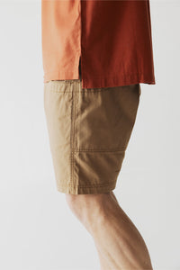 Khaki colored casual shorts with elastic waistband and cargo pockets, side view