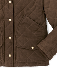 Close-up detail of quilted brown jacket showing chest pocket, snap buttons, and sleeve