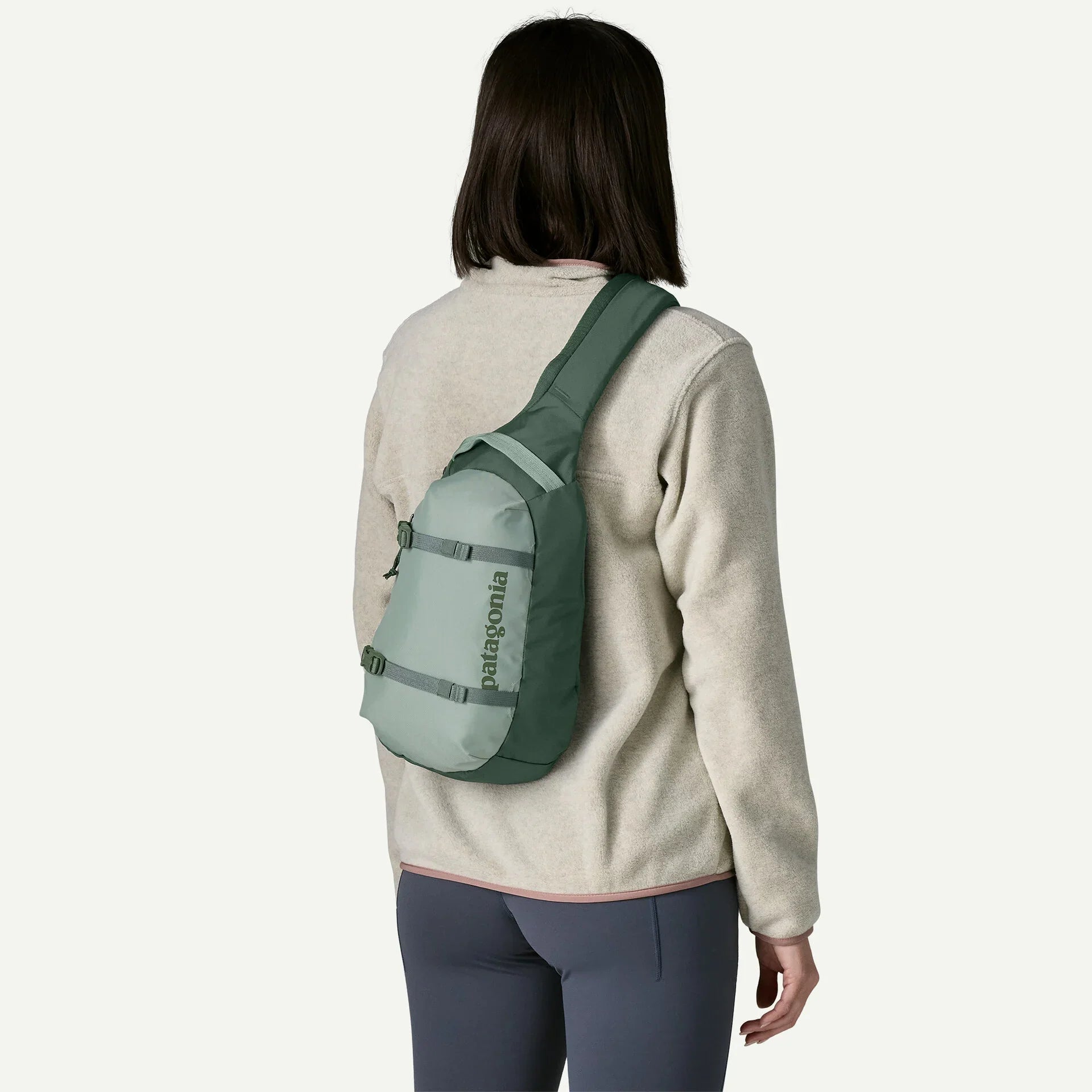 Sling bag in sage green worn diagonally across back, on-model rear view