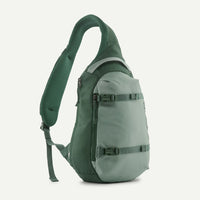 Single-strap sling bag in sage green with padded shoulder strap, front zip pockets, and buckle compression straps