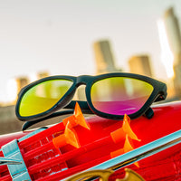 Black sunglasses with colorful gradient mirrored lenses on red sports car