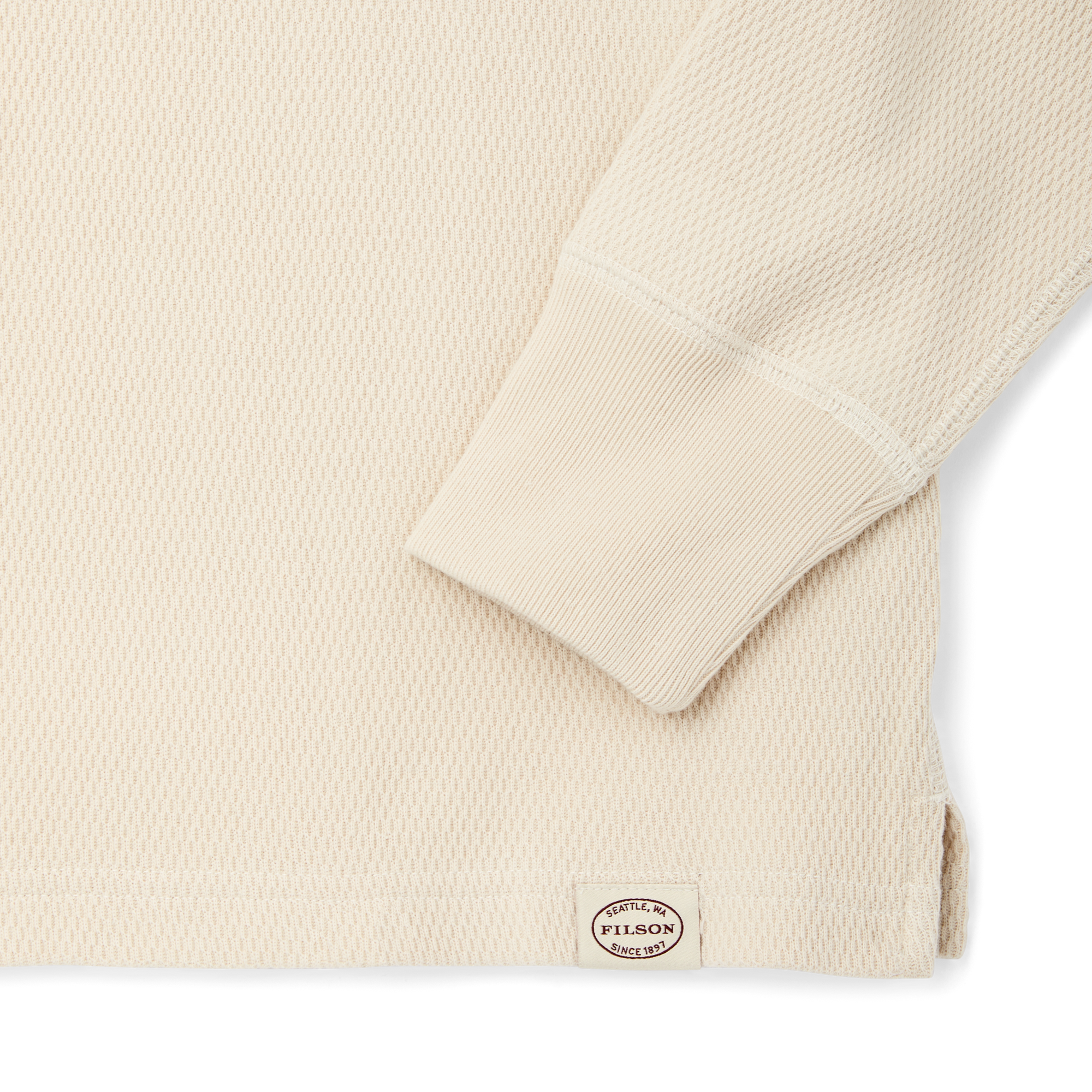 Close-up detail of waffle knit fabric sleeve cuff with ribbed trim and brand label