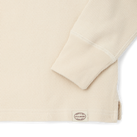 Close-up detail of waffle knit fabric sleeve cuff with ribbed trim and brand label