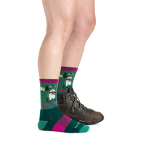 Green crew socks with raccoon camping pattern and pink accents, worn with hiking boot