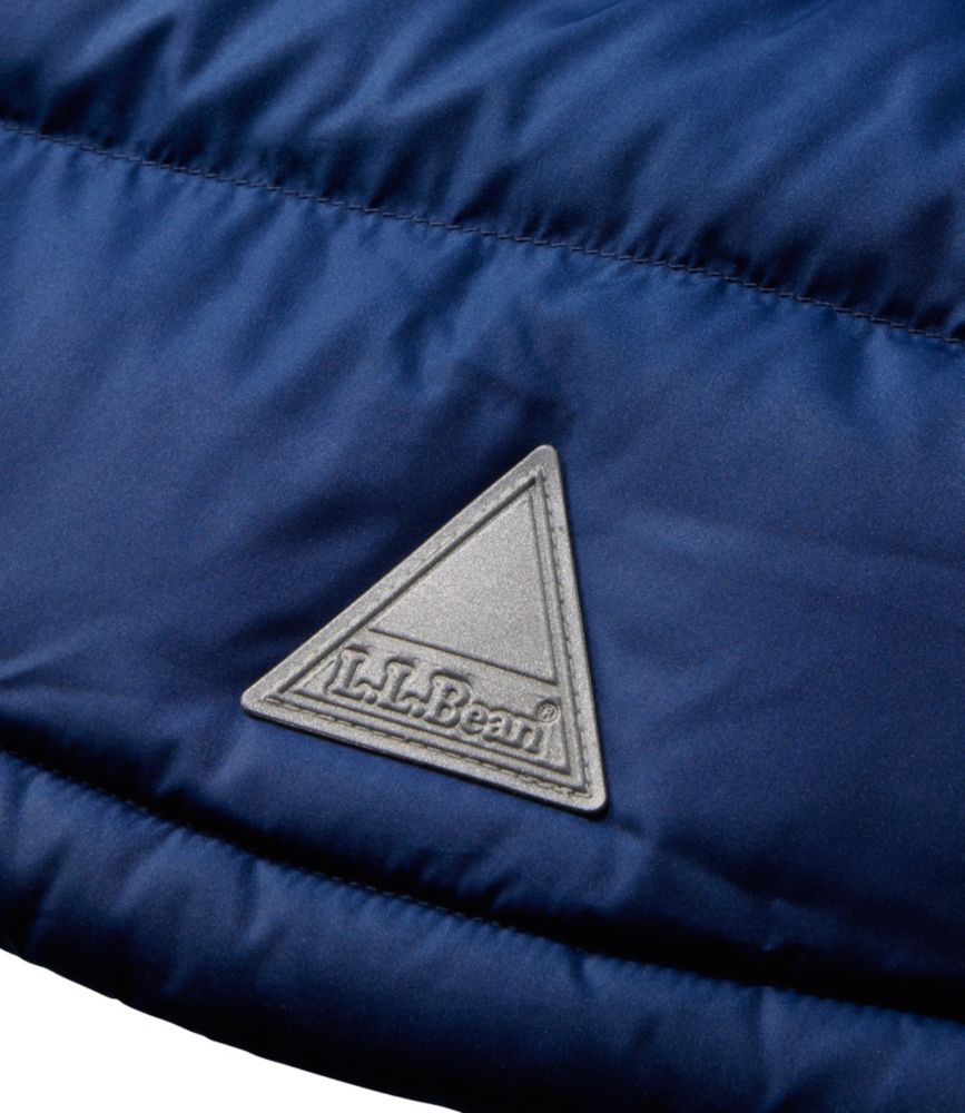 Close-up detail of quilted down jacket showing silver triangular brand logo patch