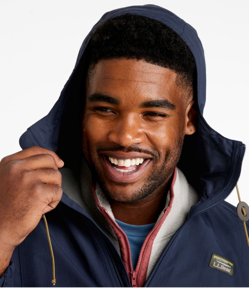 Man smiling wearing a dark navy hooded full-zip jacket with hood pulled up, layered over hoodie