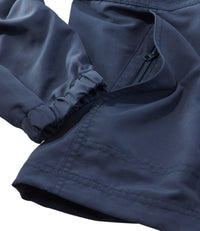 Close-up detail of navy jacket showing elastic cuff, zipper pocket, and stitched hem