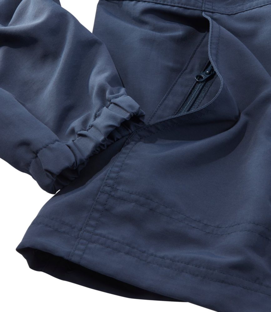 Close-up detail of navy jacket showing elastic cuff, zipper pocket, and stitched hem