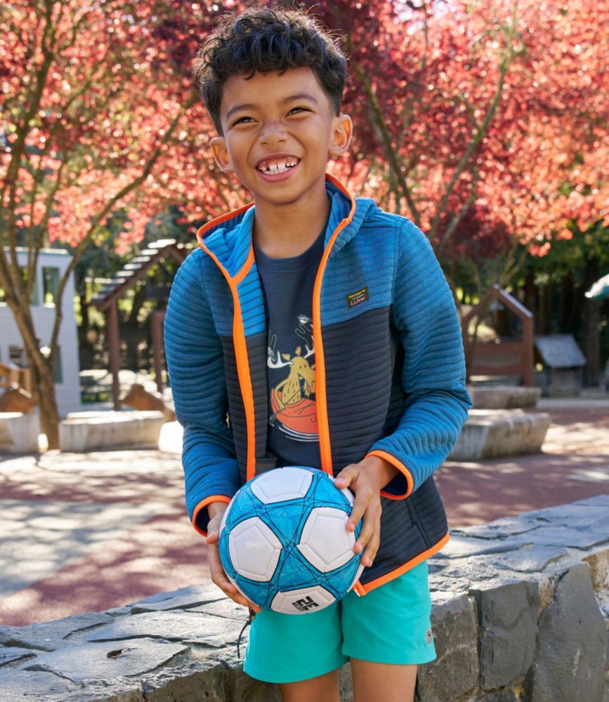Boy wearing blue colorblock zip-up hoodie with orange trim, holding soccer ball