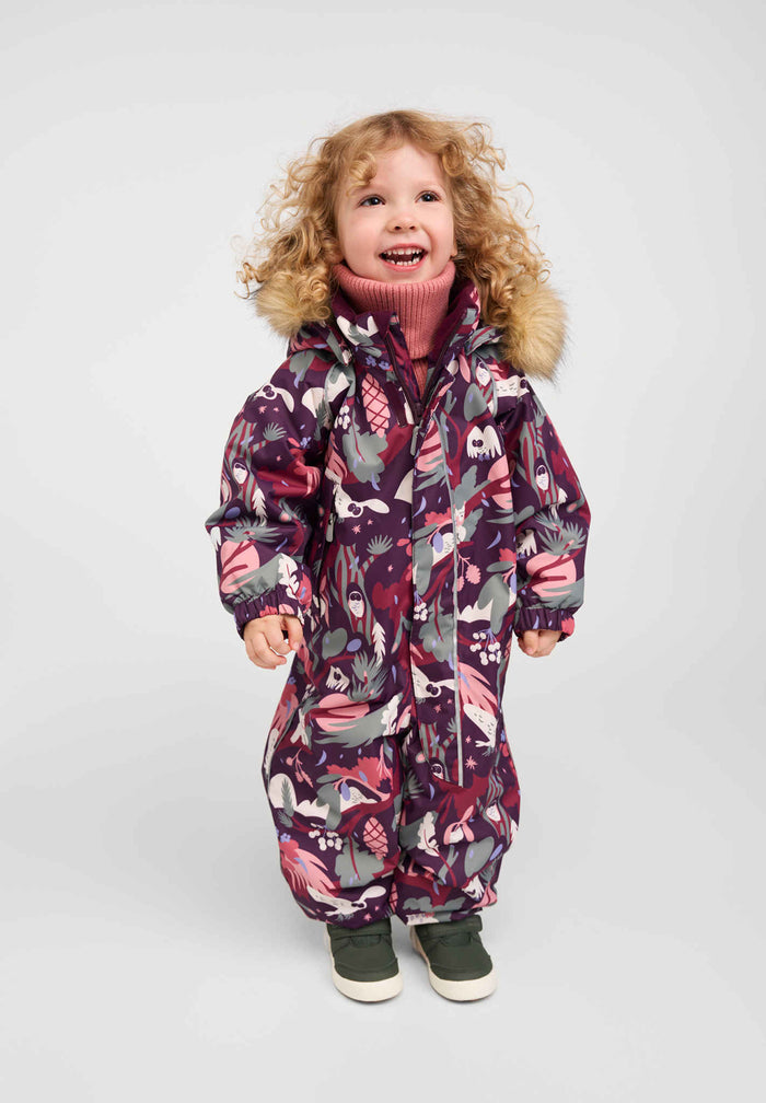 Child wearing a deep purple patterned one-piece winter overall with fur-trimmed hood, front view