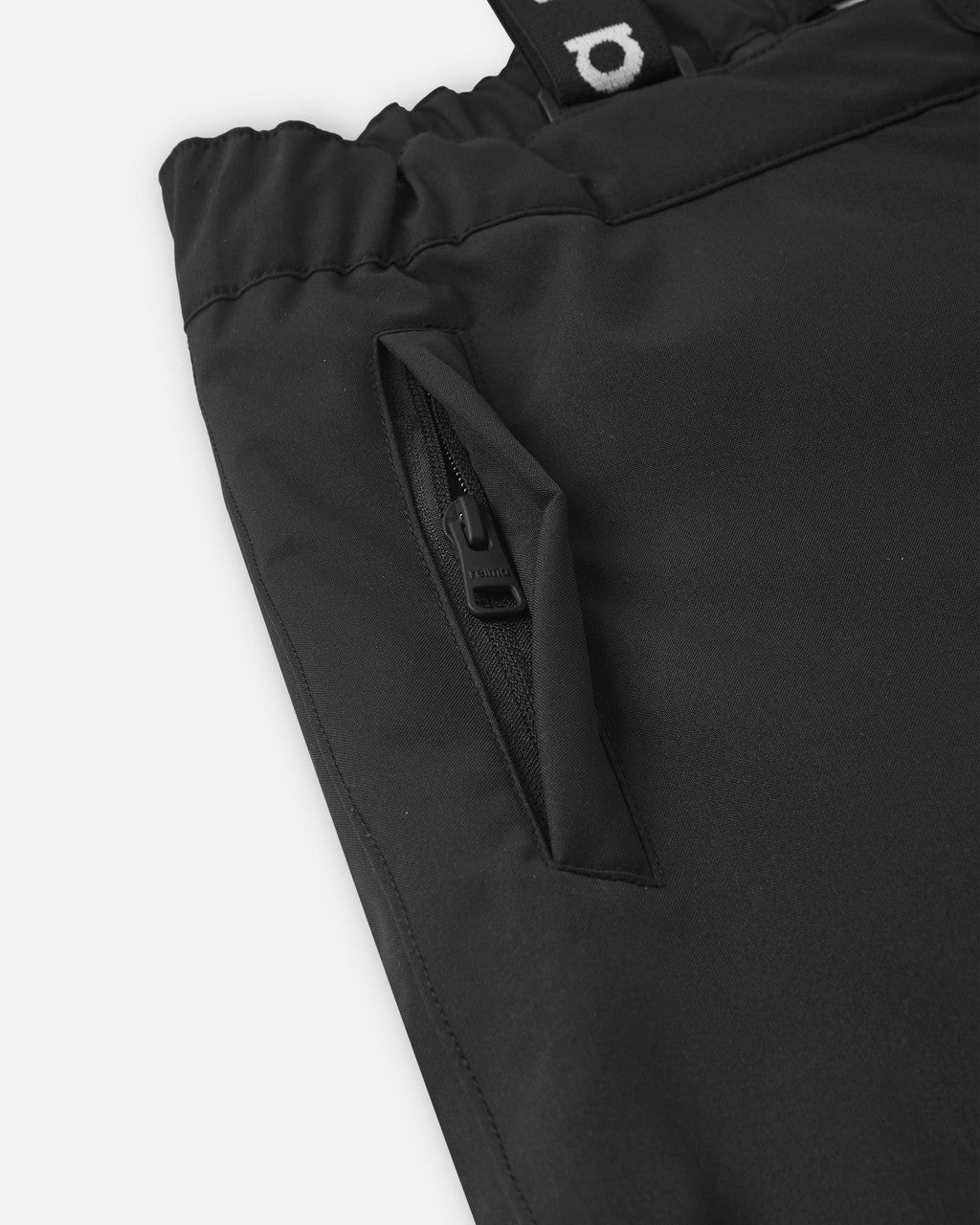 Black snow pants detail showing zippered side pocket and elastic waistband