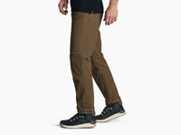 Men's rugged work pants in olive brown with contrast stitching, side view, with hiking boots
