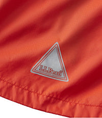 Close-up detail of red-orange jacket fabric with triangular logo patch and stitching