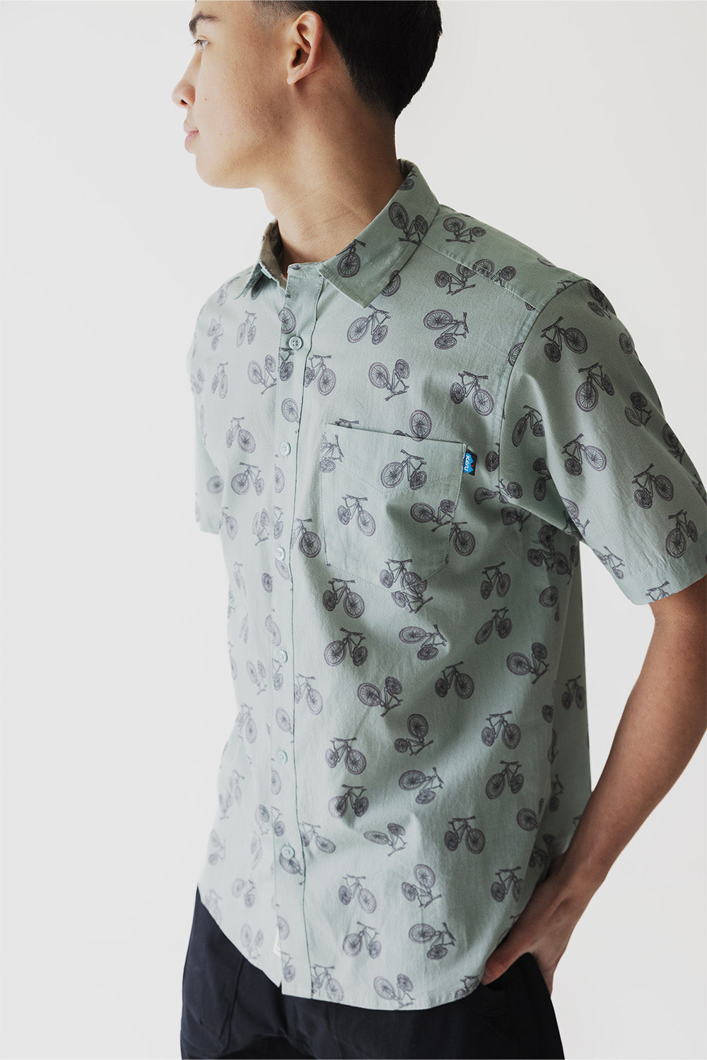 Light green button-up shirt with bicycle print pattern, side profile view