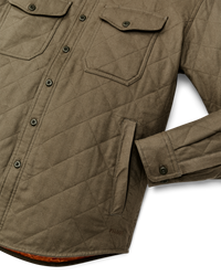 Quilted olive shirt-jacket detail shot showing chest pockets, buttons, and side pocket