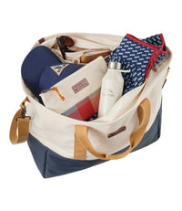 Large canvas tote bag with navy bottom panel filled with various items including water bottle and accessories