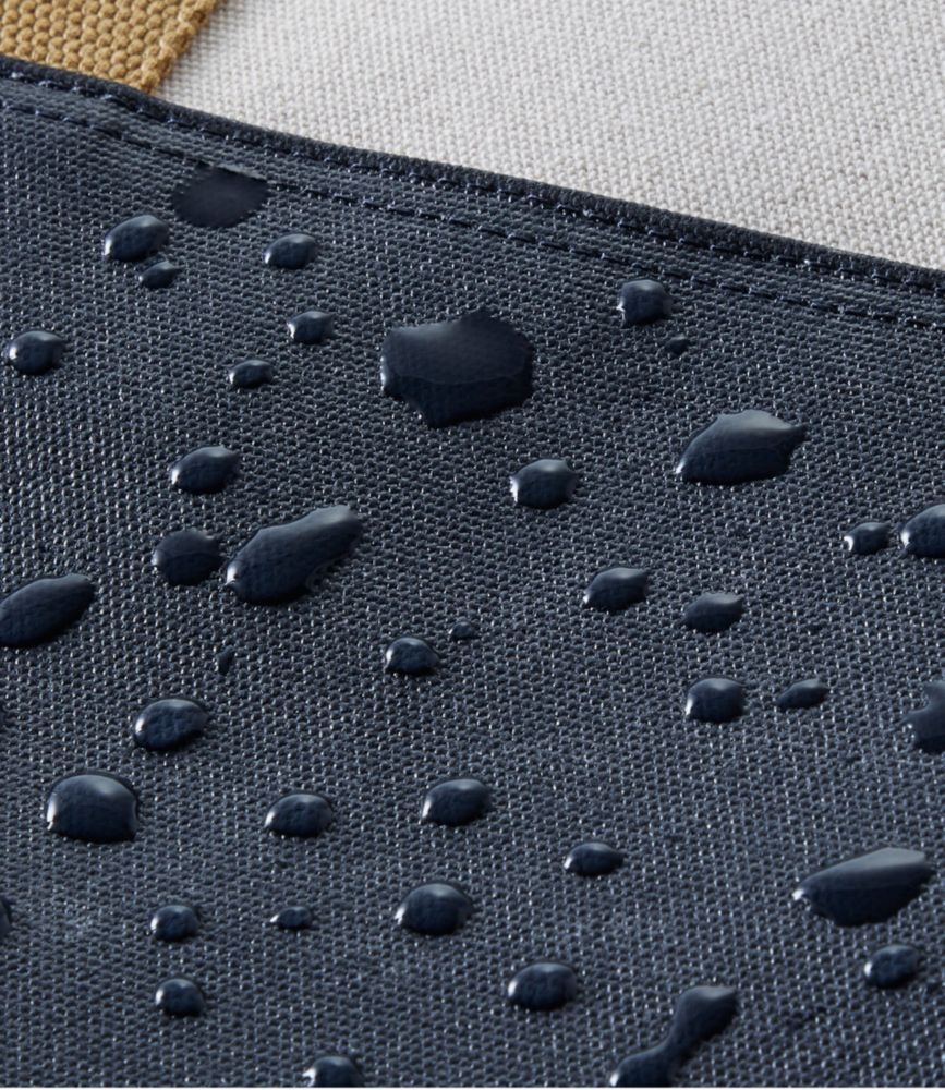 Close-up of navy blue canvas tote bag fabric showing water-resistant coating with beaded water droplets