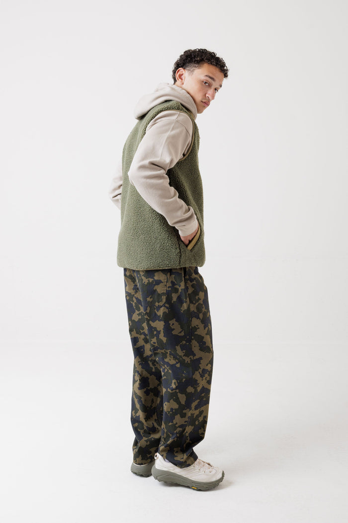 Men's sherpa fleece vest in olive green, side view, layered over beige hoodie