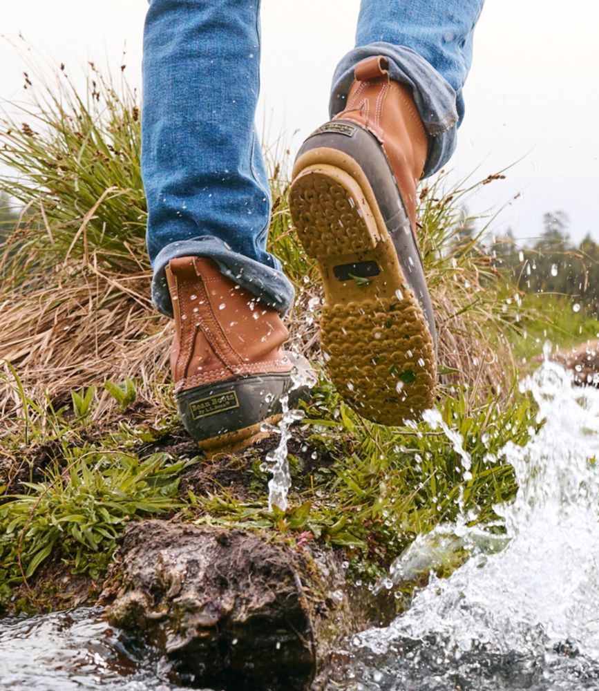 Waterproof leather boots with rubber soles stepping over wet rocks in a stream