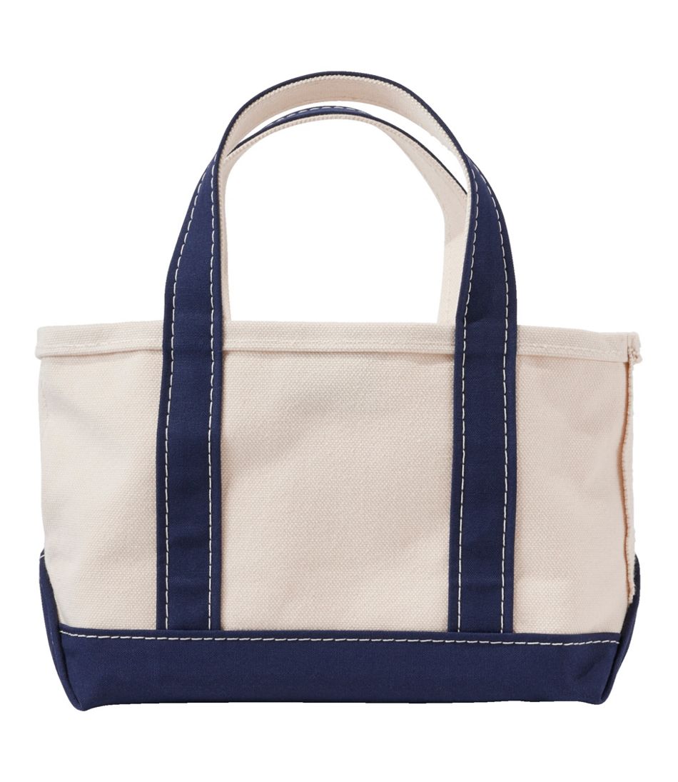Small canvas tote bag with navy blue handles, bottom trim, and contrast stitching, front view