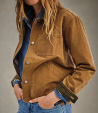 Brown field jacket with snap buttons and chest pockets worn over denim shirt