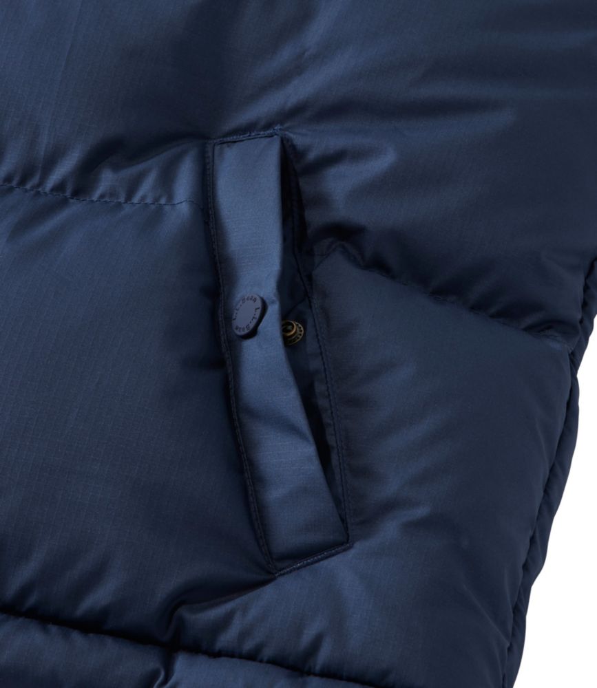 Close-up detail of quilted down vest pocket with snap button closure in navy