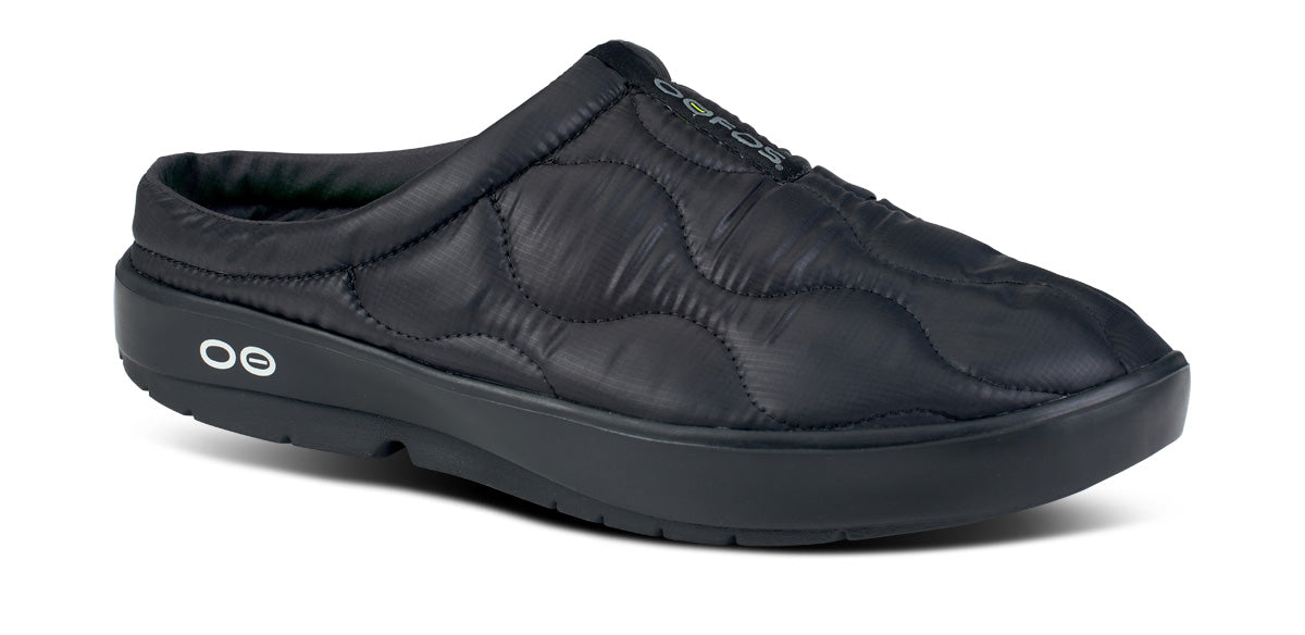 Black quilted slip-on mule with cushioned footbed and thick supportive sole, angled view