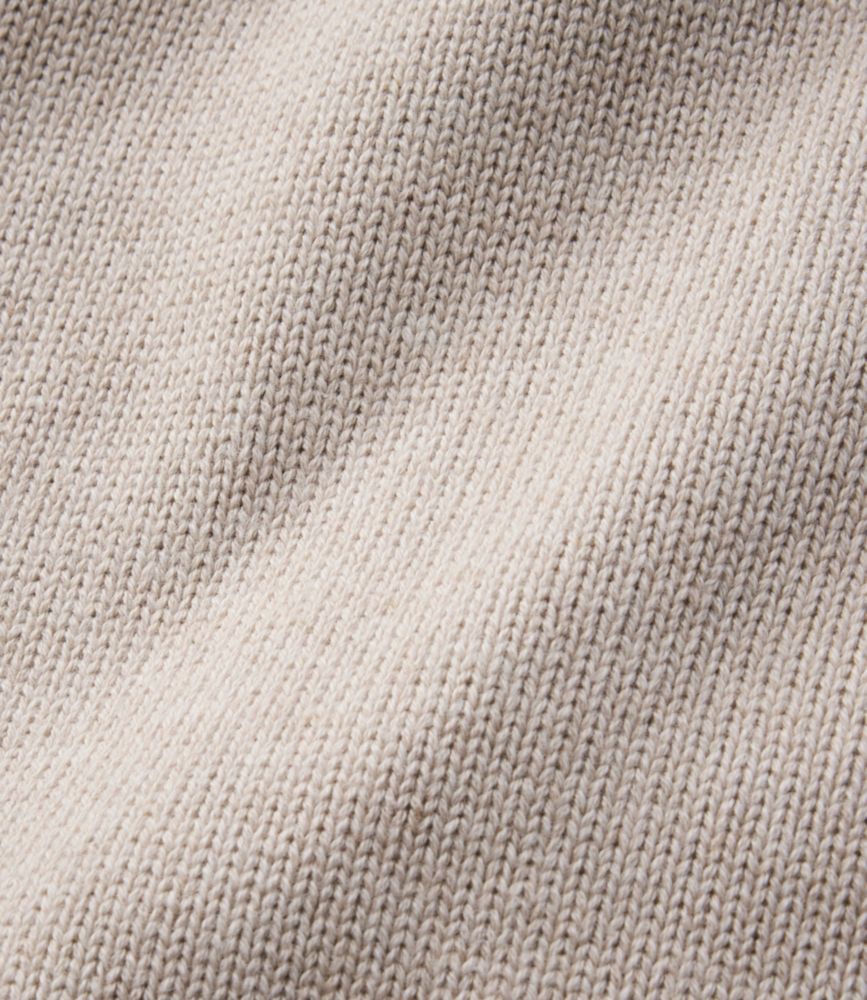 Close-up detail of knit sweater fabric in off-white, showing fine stitch texture and drape