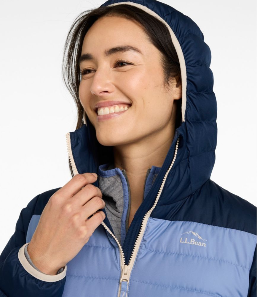 Close-up of woman wearing hooded puffer jacket with two-tone blue colorblock and cream zipper detail