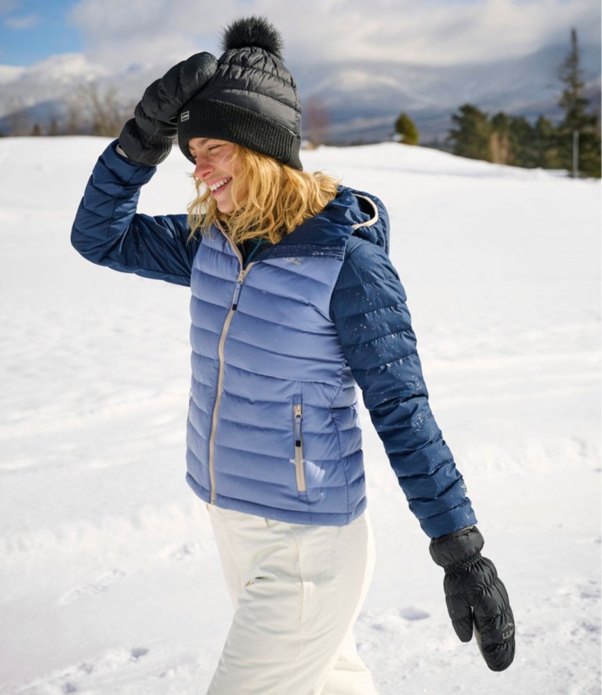 Woman wearing quilted puffer jacket with two-tone blue colorblock design, smiling in snowy outdoor setting