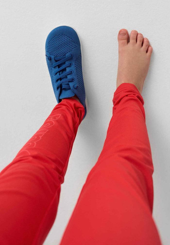 Blue knit barefoot shoes worn on feet, showing breathable mesh upper and minimal design