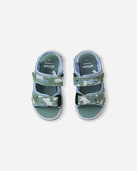 Green children's sandals with white character print and adjustable velcro straps, overhead view