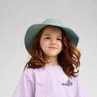 Child wearing sage green wide-brimmed sun hat with wavy hair in studio portrait
