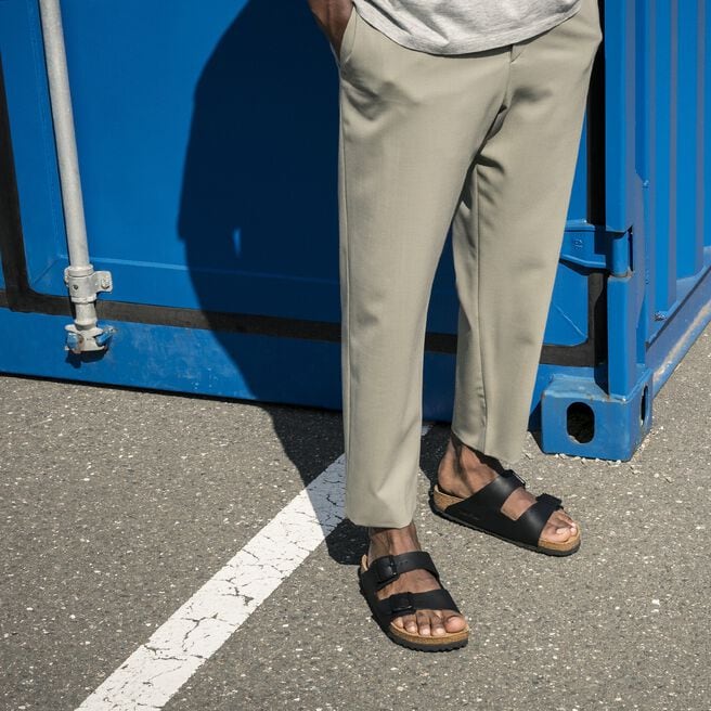 Black two-strap sandals with buckles worn on feet outdoors