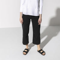 Black two-strap sandals with buckle closures worn by person in casual outfit