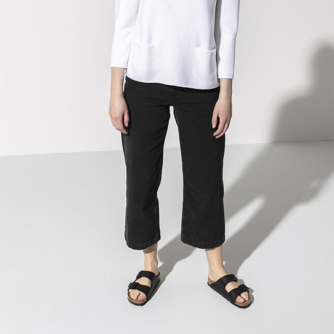Black two-strap sandals with buckle closures worn by person in casual outfit