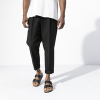 Black two-strap sandals with cork footbed worn by person in casual clothing