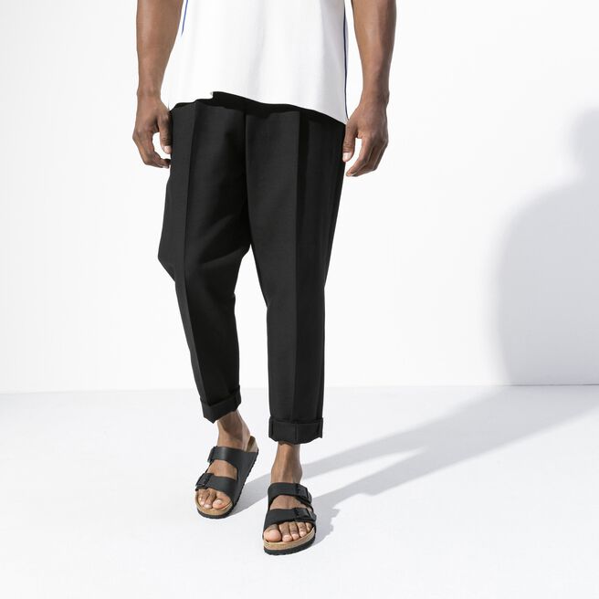 Black two-strap sandals with cork footbed worn by person in casual clothing